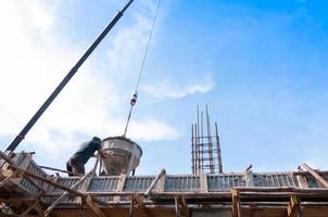 construction building workers at construction site pouring concrete in form man working at height with blue sky at construction site photo